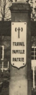 Les poteaux qui marquent l'entrée sont ornés de la francisque, emblème de l'Etat français, et de la devise "Travail. Famille. Patrie".